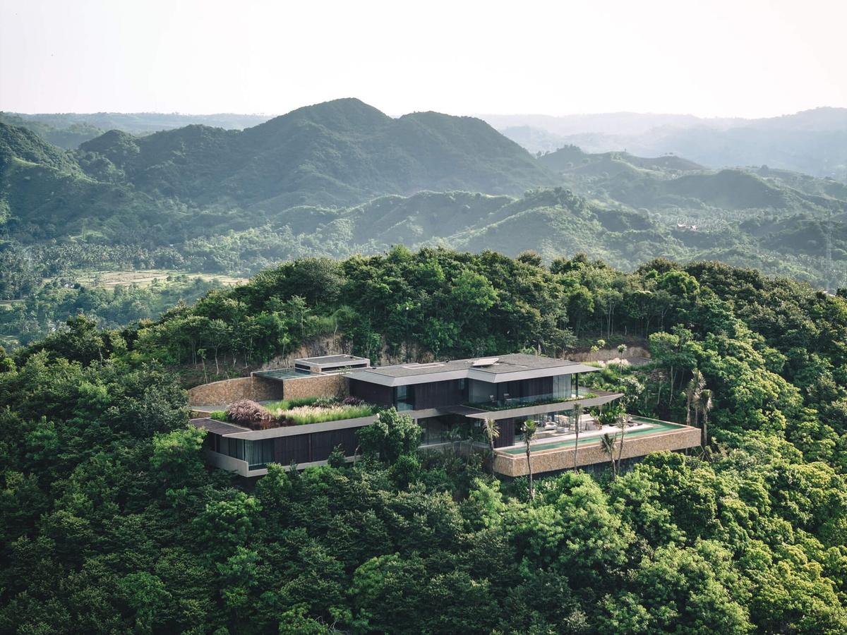 A villa with planted roofs set into forested hills, seen from the air
